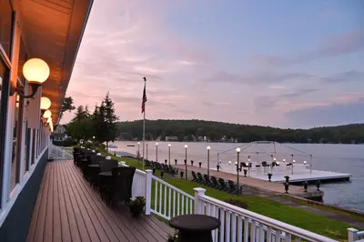 a dock with tables and chairs on the water at Chestnut Inn at Oquaga Lake in Deposit