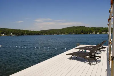 a wooden dock with benches on the water at Chestnut Inn at Oquaga Lake in Deposit