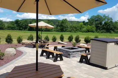 a patio with two picnic tables and an umbrella at Vista Lodge Benton PA near Ricketts Glen State Park in Benton