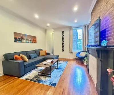 a living room with a blue couch and a brick wall at Large Home - Great Location - 15 Minutes to NYC in Hoboken