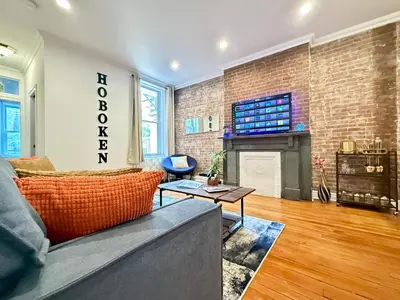 a living room with a couch and a brick wall at Large Home - Great Location - 15 Minutes to NYC in Hoboken