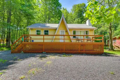 a yellow house with a large front porch at Pet-Friendly Pocono Lake Cabin with Community Pool! in Pocono Lake