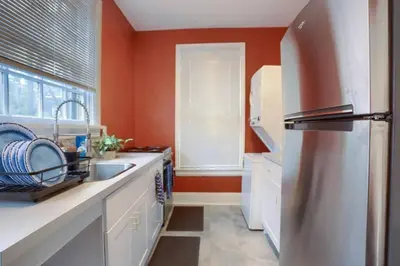 a kitchen with orange walls and a stainless steel refrigerator at Charming Downtown Retreat Steps from Capitol Bldg in Harrisburg