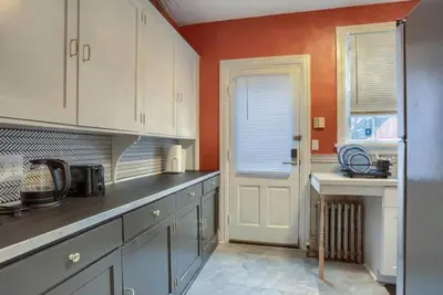 a kitchen with white cabinets and an orange wall at Charming Downtown Retreat Steps from Capitol Bldg in Harrisburg