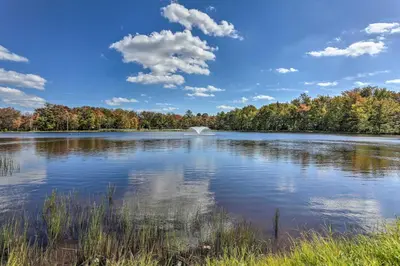 a large lake with trees in the background at Deck and Screened Porch Pocono Lake Vacation Rental in Pocono Lake
