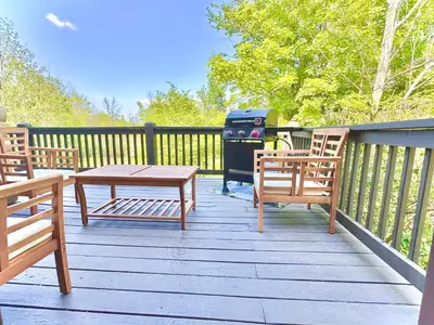 a grill on a deck with two chairs and a table at Big Bear Cabin in Corning