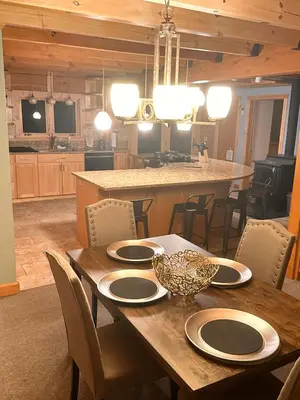 a dining room table with chairs and a kitchen at Big Bear Cabin in Corning