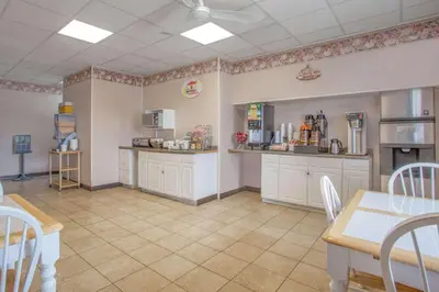 a large kitchen with white cabinets and a table and chairs at Travelodge by Wyndham Carlisle North in Carlisle