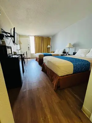 a hotel room with two beds and a desk at Travelodge by Wyndham Carlisle North in Carlisle