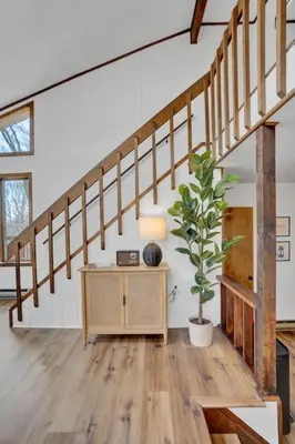 a living room with a staircase and a potted plant at Serene & Fun Family Gem ~ Big Bass Lake Community! in Gouldsboro