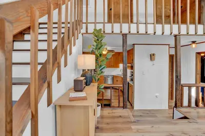 a room with wooden stairs and a table with a lamp at Serene & Fun Family Gem ~ Big Bass Lake Community! in Gouldsboro