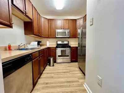 a kitchen with wooden cabinets and stainless steel appliances at Luxury Condo Near NYC, MetLife & American Dream in Passaic