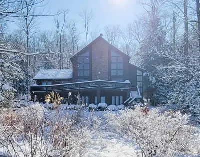 a large house with snow on the ground at Lakefront Sunsets, Hot Tub, Pool Table, Kayaks in Lake Ariel