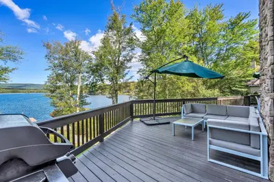 a wooden deck with a couch and an umbrella at Lakefront Sunsets, Hot Tub, Pool Table, Kayaks in Lake Ariel