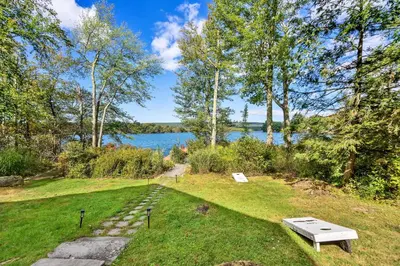a picnic table in the grass next to a lake at Lakefront Sunsets, Hot Tub, Pool Table, Kayaks in Lake Ariel