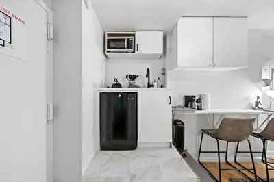 a kitchen with white cabinets and a black refrigerator at Elevate Apartment at Times Square - Cozy Studio in Times Square and Nearby Restaurants in New York