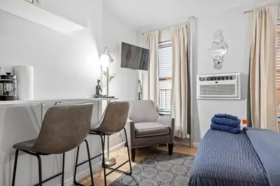 a bedroom with a bed and chairs in a room at Elevate Apartment at Times Square - Cozy Studio in Times Square and Nearby Restaurants in New York