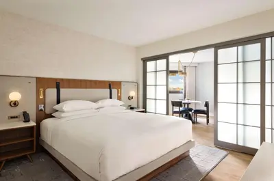 a bedroom with a large white bed and a dining room at Hyatt Regency New Brunswick in New Brunswick