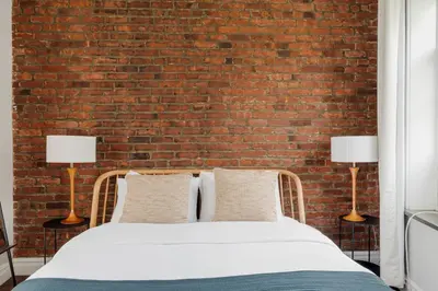 a bed in front of a brick wall with two lamps at West Village 1br w high ceilings skylight wd NYC-1172 in New York