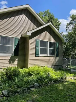 a brown house with a fence in front of it at Falls Edge Farm Cottage in Benton