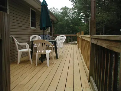 a wooden deck with a table and chairs and an umbrella at Falls Edge Farm Cottage in Benton