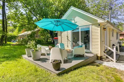 a patio with chairs and a blue umbrella at All-Season Vernon Township Lake House Retreat! in Vernon Township