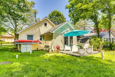a house with a deck with a boat and an umbrella at All-Season Vernon Township Lake House Retreat! in Vernon Township