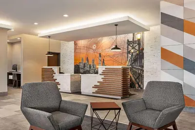 a lobby with two chairs and a mural of a city at La Quinta Inn & Suites by Wyndham Mount Laurel Moorestown in Mount Laurel