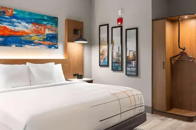 a bedroom with a white bed and paintings on the wall at La Quinta Inn & Suites by Wyndham Mount Laurel Moorestown in Mount Laurel
