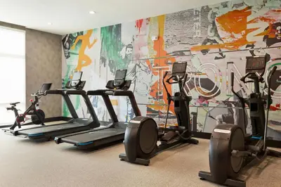 a gym with several tread machines in front of a mural at La Quinta Inn & Suites by Wyndham Mount Laurel Moorestown in Mount Laurel