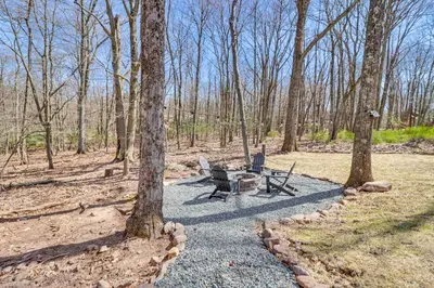 a picnic table and two chairs in the woods at Walk to Water Park Split-Rock Resort Home with Deck in Lake Harmony