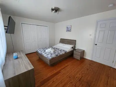 a bedroom with a bed and a tv and wooden floors at RentalsOP NJ01 Full house minutes from NYC, near to metlife, American Dream in Hackensack
