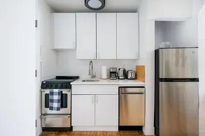 a kitchen with white cabinets and a stainless steel refrigerator at 444-3F Newly renovated 1BR in Hell's Kitchen in New York