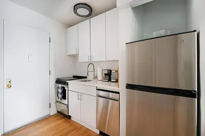 a kitchen with white cabinets and a stainless steel refrigerator at 444-3F Newly renovated 1BR in Hell's Kitchen in New York
