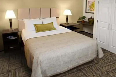 a hotel room with a large bed and two lamps at Candlewood Suites Sayre by IHG in Sayre