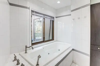 a white bathroom with a tub and a window at Spacious King of Prussia Home with 2 Game Rooms in King of Prussia