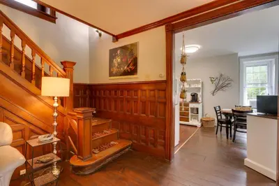 a living room with wood paneling and a staircase at Historic Home on Farm, 15 Mi to Williamsport! in Antes Fort