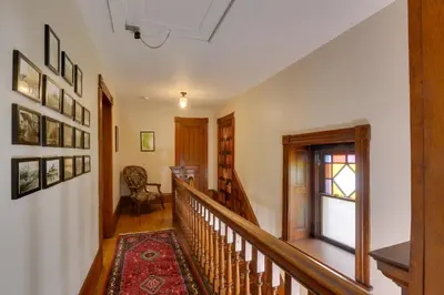 a hallway with a staircase with a window and a rug at Historic Home on Farm, 15 Mi to Williamsport! in Antes Fort
