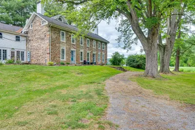 a large brick house with a tree in the yard at Historic Home on Farm, 15 Mi to Williamsport! in Antes Fort