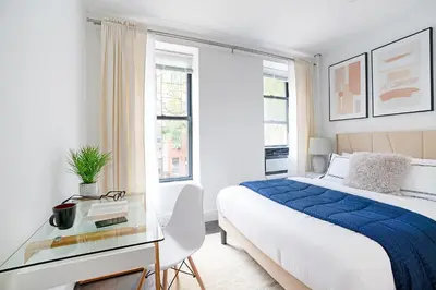 a white bedroom with a bed and a glass table at 444-2C Newly renovated 1BR in Hell's Kitchen in New York