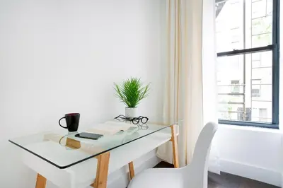 a glass desk with a potted plant and a chair at 444-2C Newly renovated 1BR in Hell's Kitchen in New York