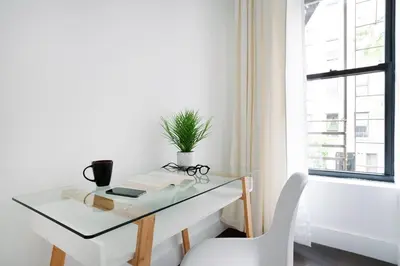 a glass desk with a potted plant and a chair at 444-4F Newly renovated 1BR in Midtown West in New York