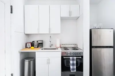 a white kitchen with a stove and a refrigerator at 444-4F Newly renovated 1BR in Midtown West in New York