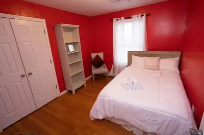 a red bedroom with a bed with two towels on it at Family 3-bedroom home (2nd floor near EWR/Outlet) in Elizabeth