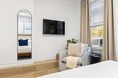 a bedroom with a bed and a chair and a tv at Convenient 2BR - Walking distance to Times Square in New York