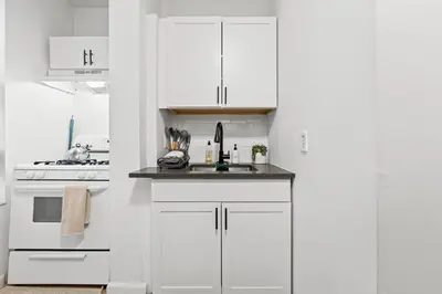 a white kitchen with white cabinets and a sink at Convenient 2BR - Walking distance to Times Square in New York