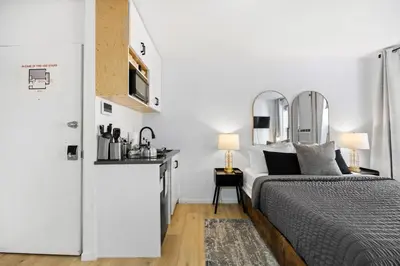 a white bedroom with a bed and a kitchen at Midtown Studio - Walking Distance to Times Square in New York