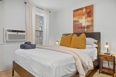 a white bedroom with a large bed with yellow pillows at Times Square Studio near Restaurants & Shopping in New York