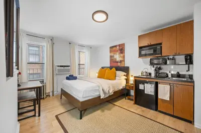 a bedroom with a large bed and a kitchen at Times Square Studio near Restaurants & Shopping in New York