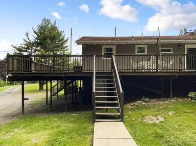 a house with a deck with a staircase leading to it at Haven Retreat in Catskills w Hot Tub & Bar Hall in Sundown